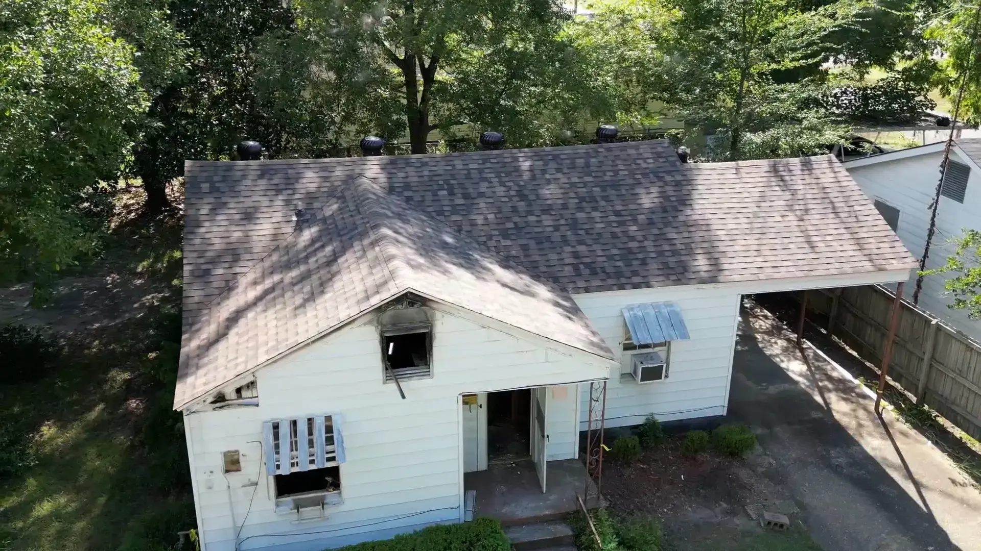 Older white house with its storm damage repaired and a restored shingle roof